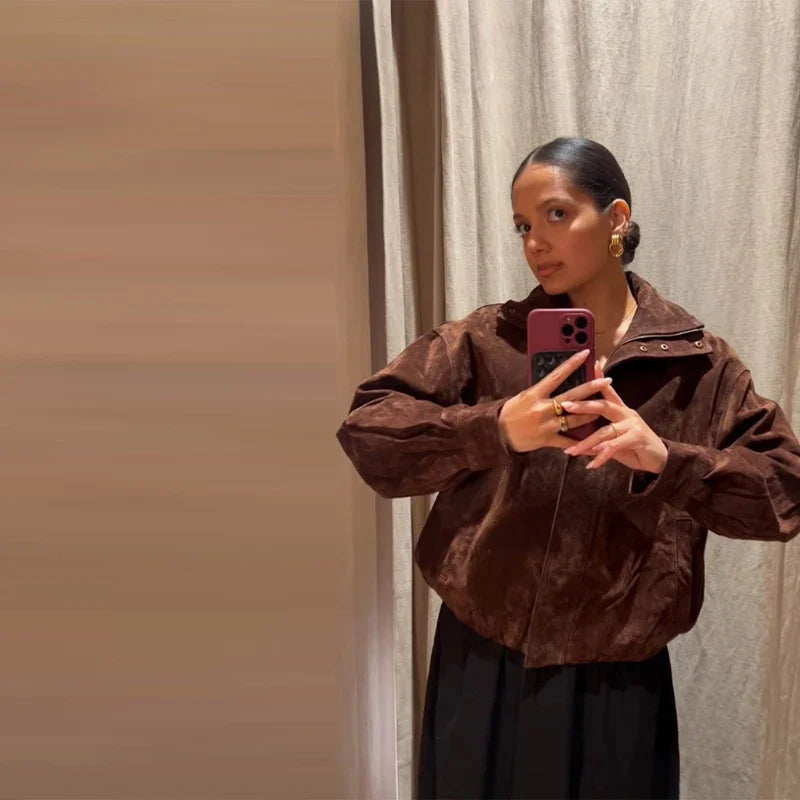 Person wearing a brown jacket taking a mirror selfie.
