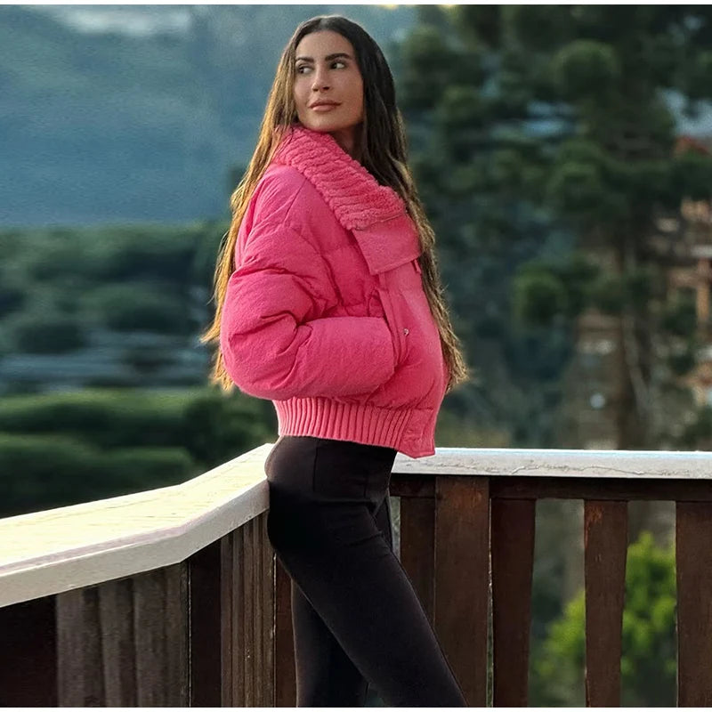 Woman in a pink jacket standing on a wooden deck with a blurred natural background