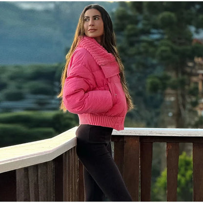 Woman in a pink jacket standing on a wooden deck with a blurred natural background