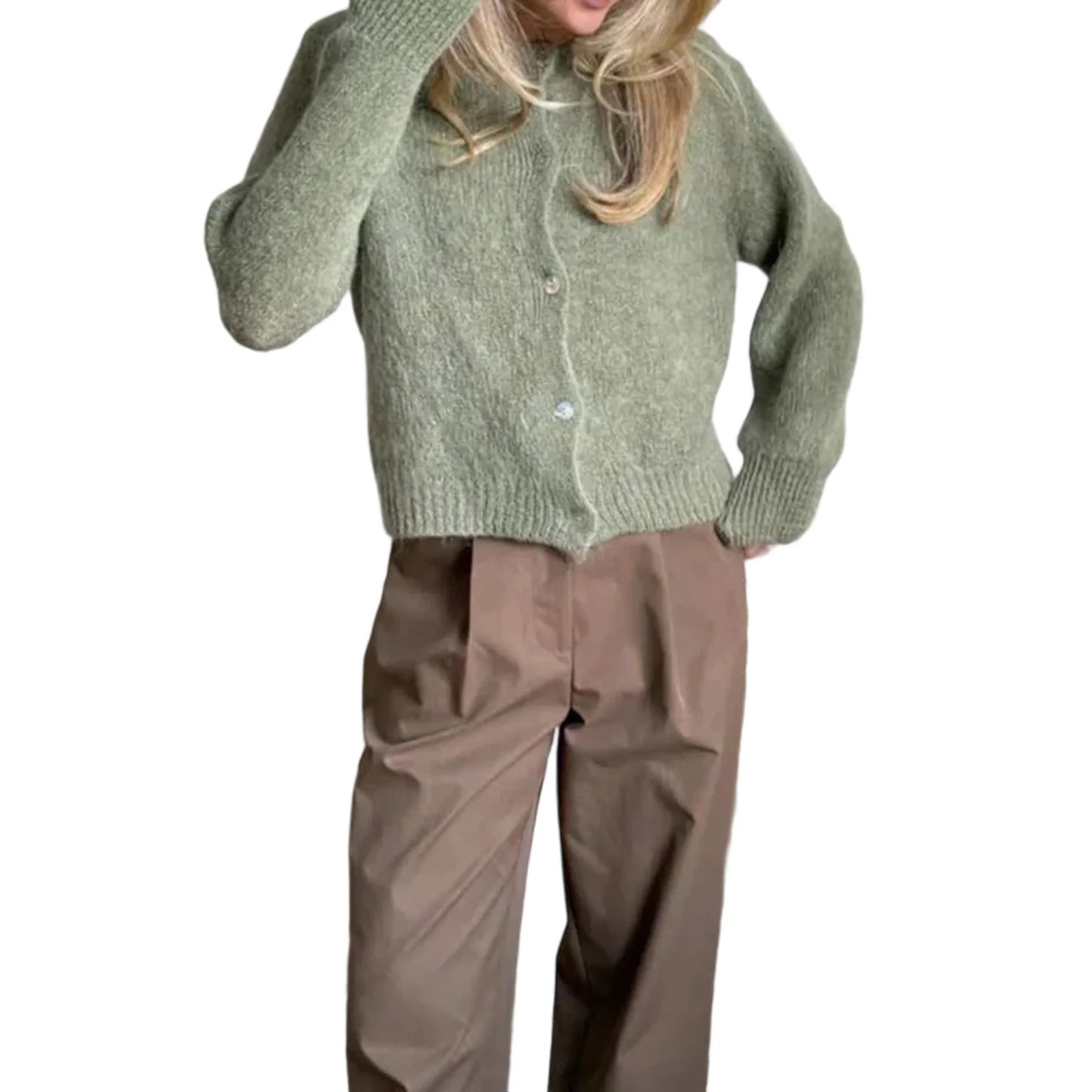 Person wearing a green knitted cardigan and brown pants on a white background
