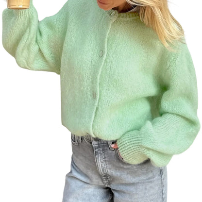 Person wearing a light green sweater and gray jeans on a white background