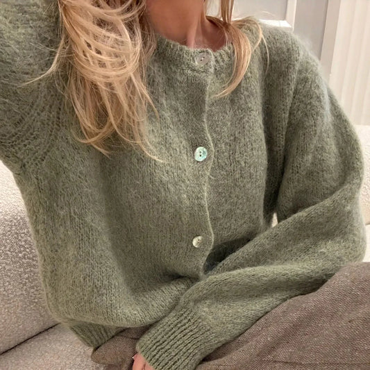 Person wearing a green knitted cardigan sitting on a couch.