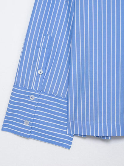 Close-up of a blue and white striped shirt with buttons on a light gray background