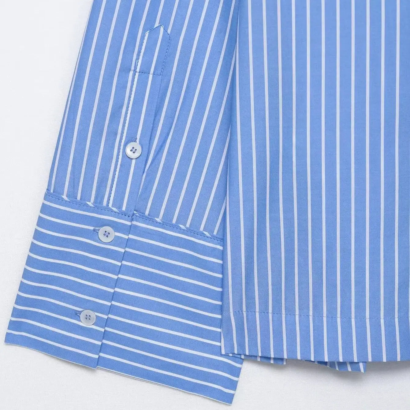 Close-up of a blue and white striped shirt with buttons on a light gray background