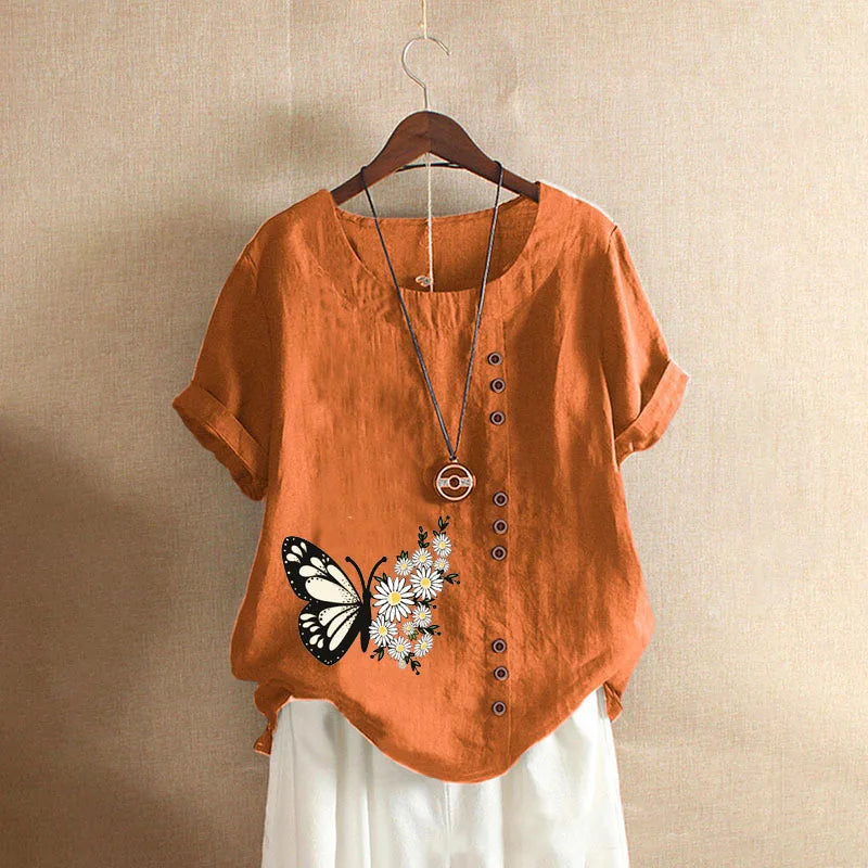 Orange shirt with butterfly and flower design on a hanger against a beige background