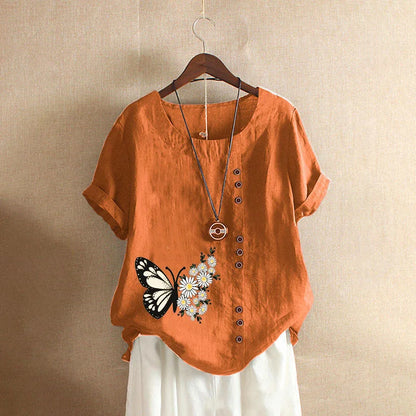 Orange shirt with butterfly and flower design on a hanger against a beige background