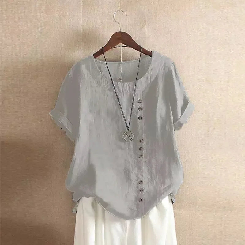 Light gray blouse with buttons on a hanger against a beige wall