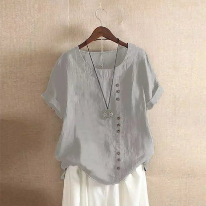 Light gray blouse with buttons on a hanger against a beige wall