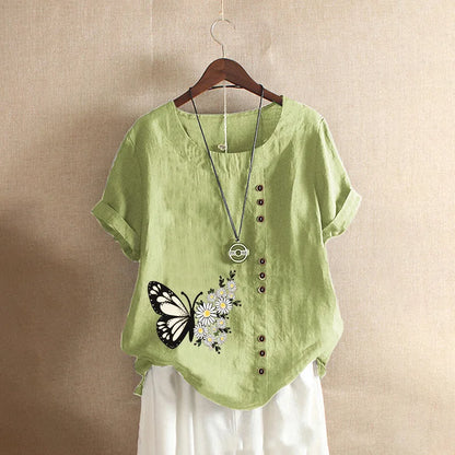 Green shirt with butterfly and flower design on a hanger against a beige background