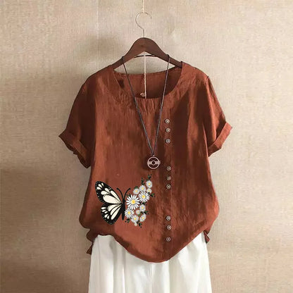 Brown shirt with butterfly and floral design on a hanger against a beige wall.
