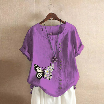 Purple shirt with butterfly and flower design on a hanger against a beige wall