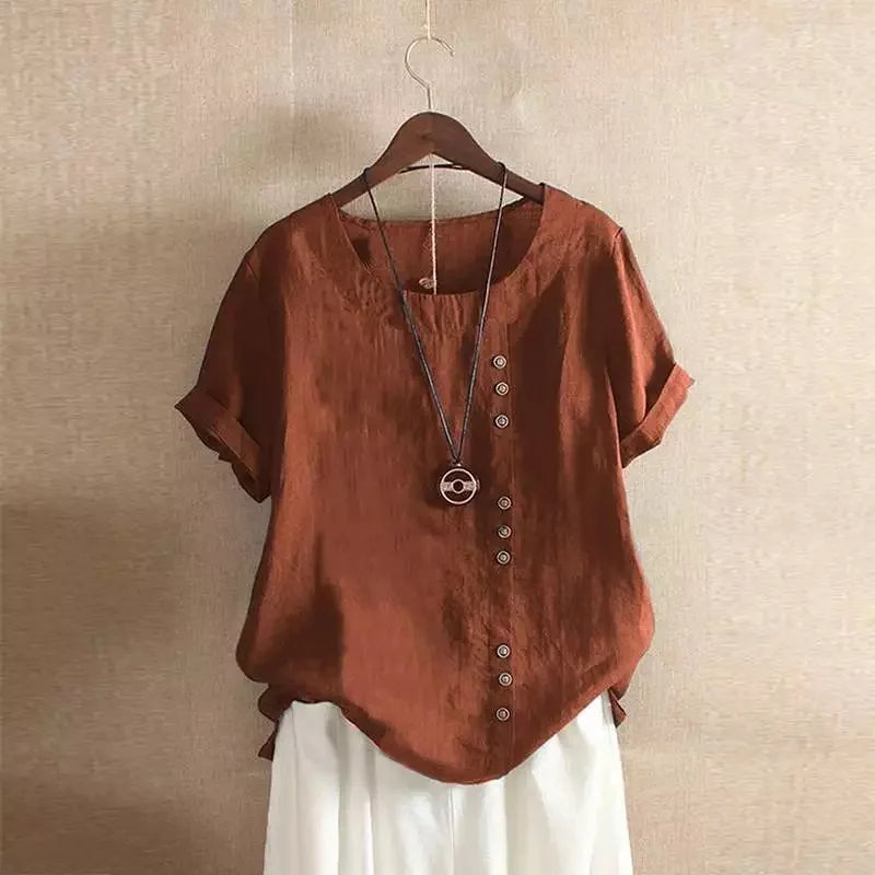 Brown blouse with buttons and a necklace on a hanger against a beige wall.