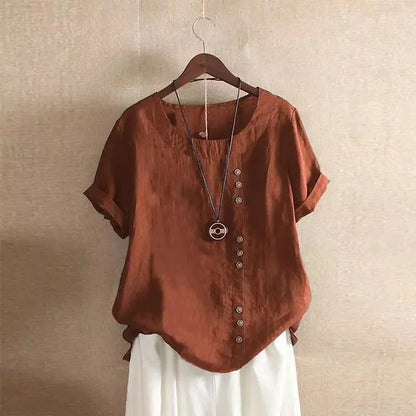 Brown blouse with buttons and a necklace on a hanger against a beige wall.