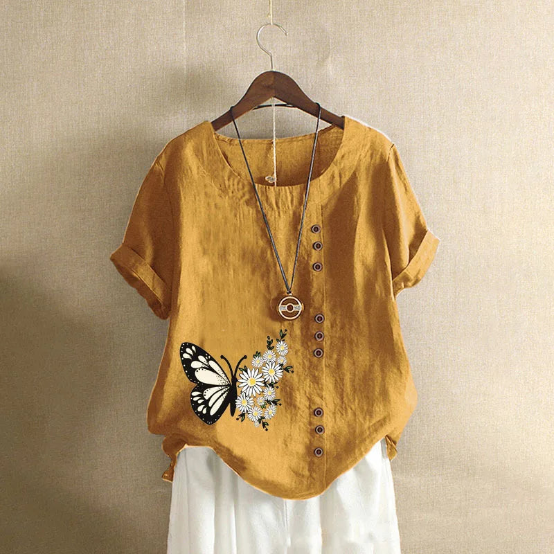 Yellow shirt with butterfly and flower design on a hanger against a beige background