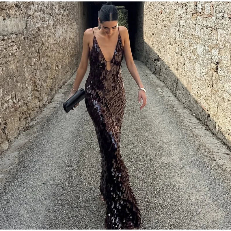 Woman in a sequined dress walking down a narrow stone alley.