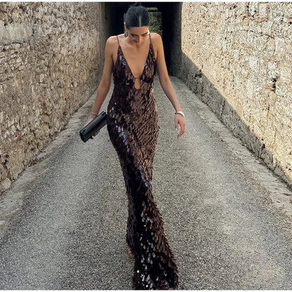 Woman in a sequined dress walking down a narrow stone alley.