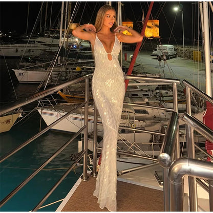 Woman in a white evening gown standing on a dock with boats in the background