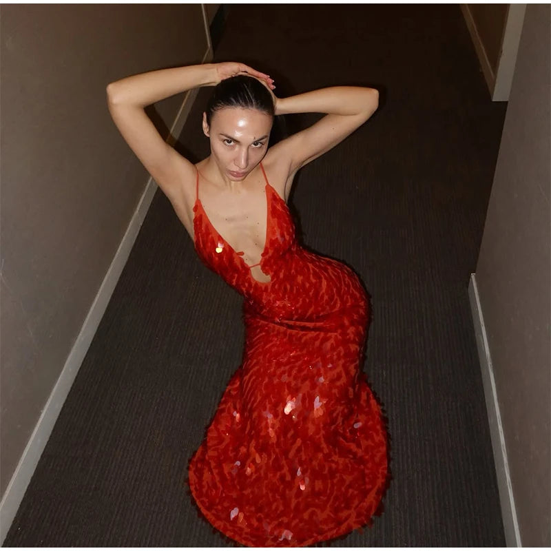 Woman in a red dress lying on a dark floor.