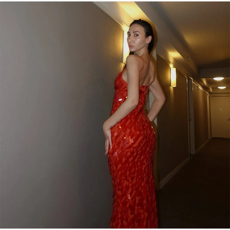 Woman in a red dress standing in a dimly lit hallway.