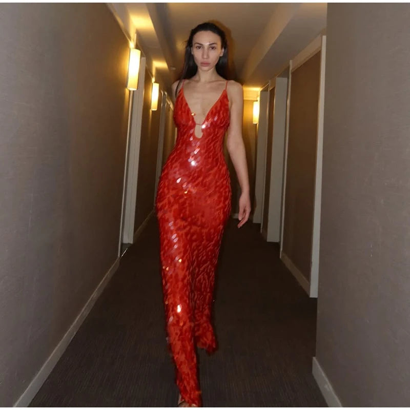 Woman in a red sequin dress walking down a dimly lit hallway.
