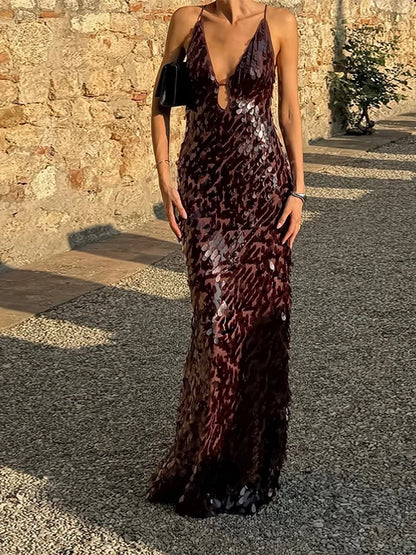 Person wearing a sequin dress standing against a stone wall.