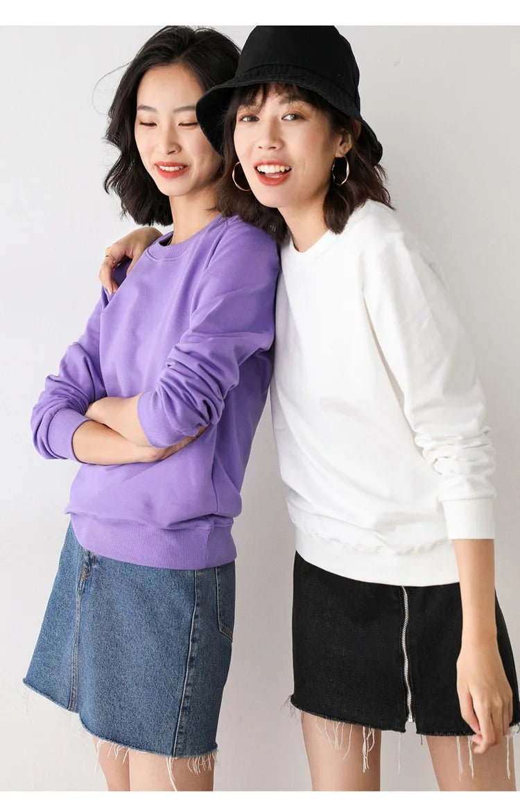 Two women wearing casual outfits with a plain background