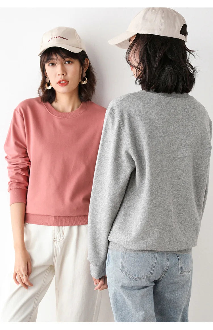 Two people wearing pink and gray sweaters with white pants and beige caps.
