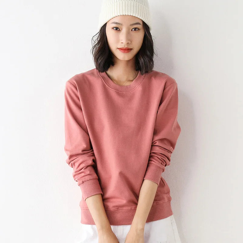 Person wearing a pink sweatshirt and white beanie against a plain background