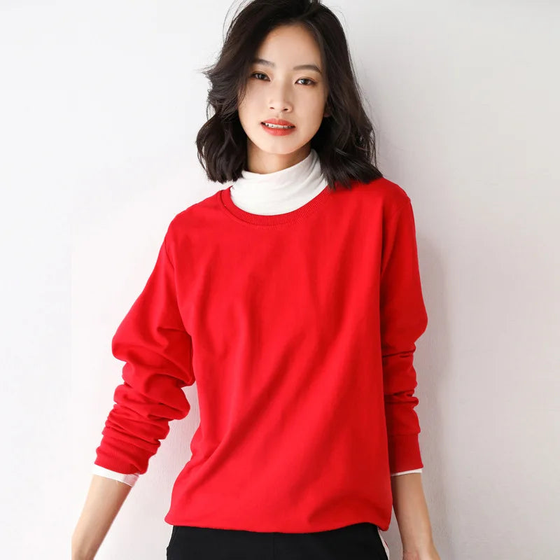 Person wearing a red sweater over a white shirt against a plain background