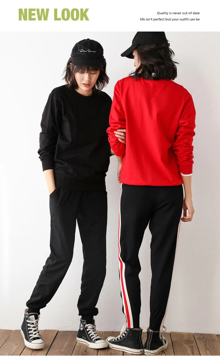 Two people wearing black and red outfits with a plain background