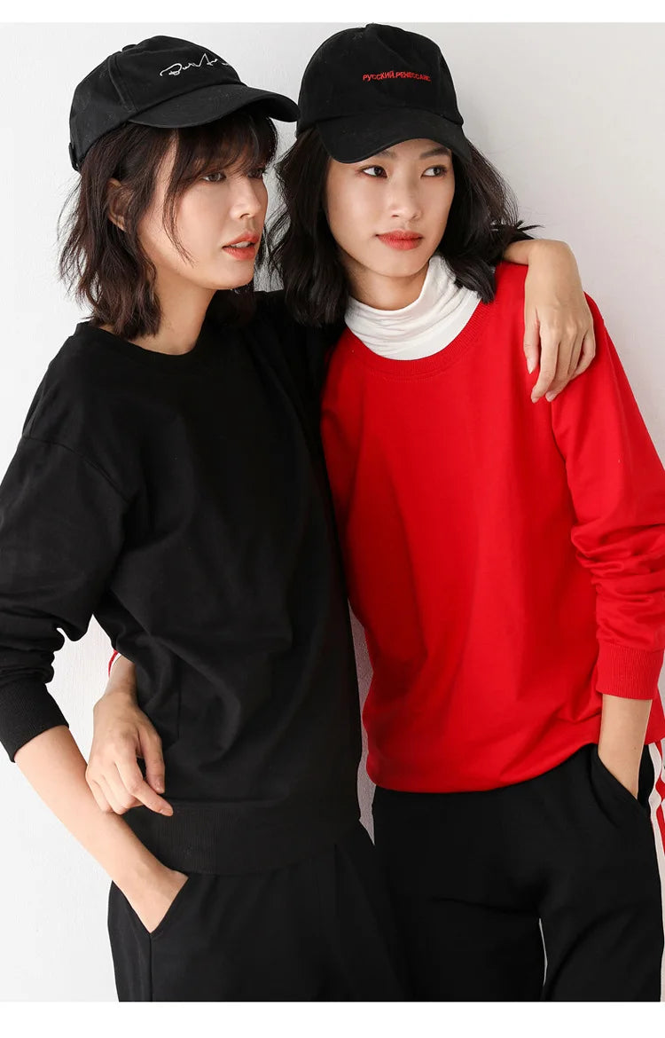 Two people wearing black and red outfits with matching hats on a white background