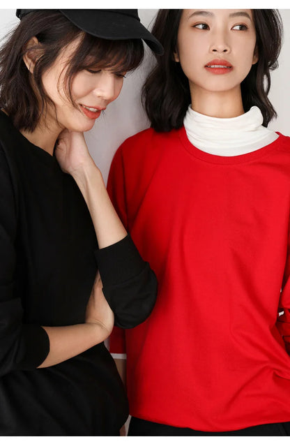 Two women, one in a black outfit and the other in a red outfit, standing close together.