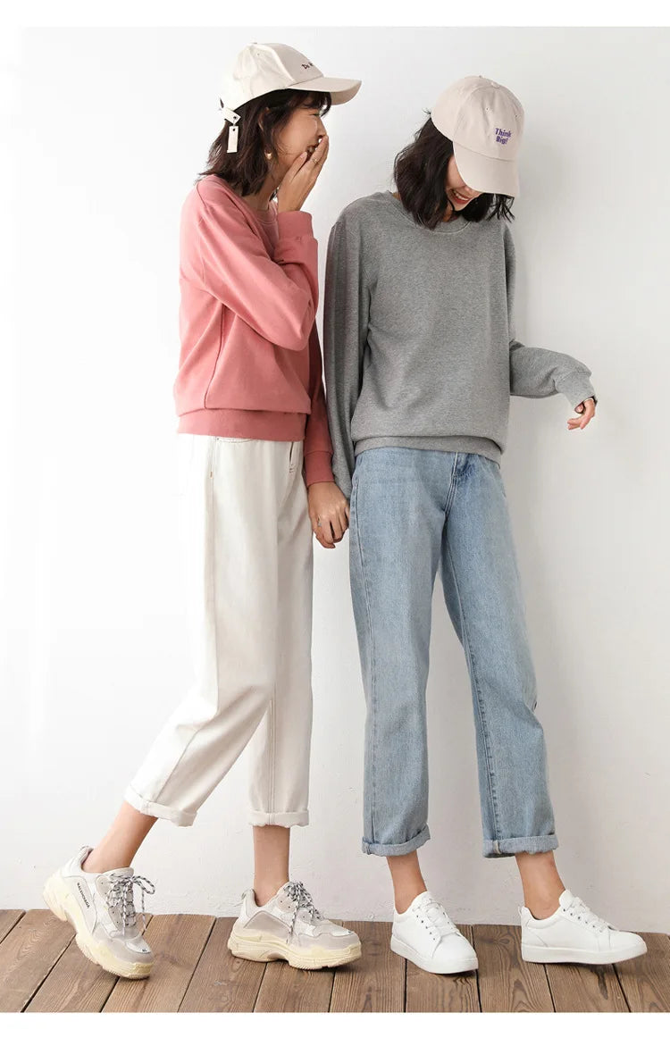 Two people wearing casual clothing and hats against a white wall.