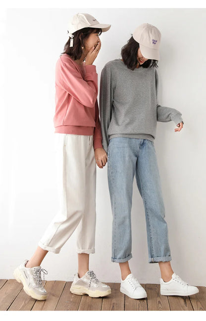 Two people wearing casual clothing and hats against a white wall.