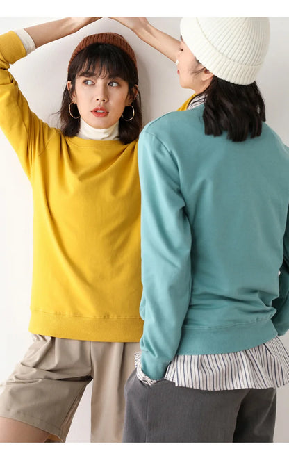 Two people wearing colorful sweaters and hats against a plain background