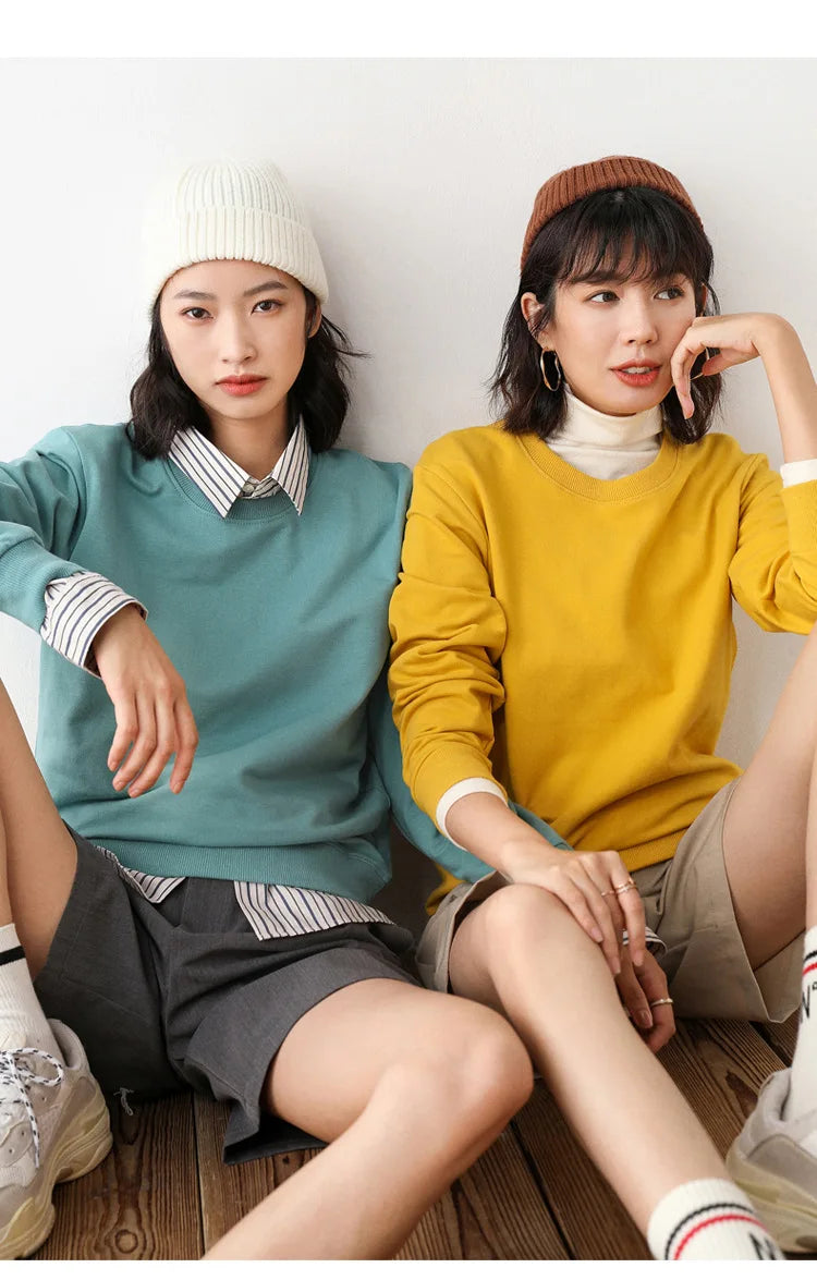 Two people sitting on the floor wearing colorful sweaters and hats.