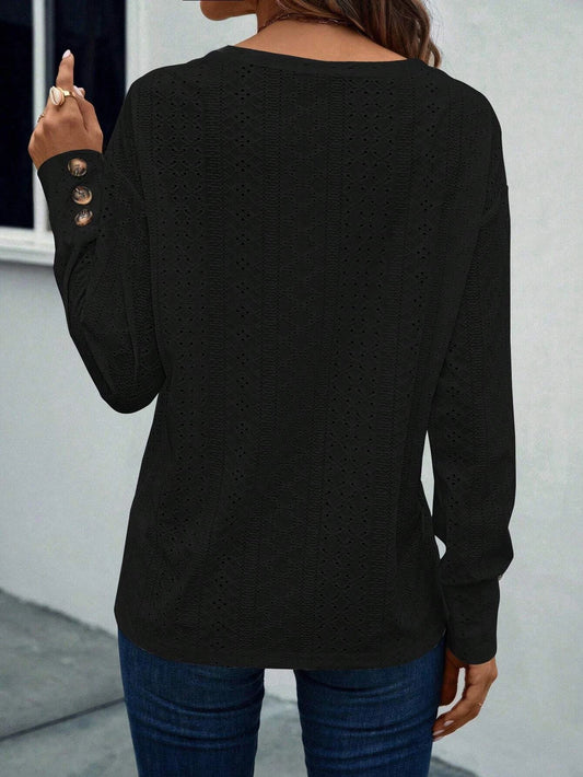 Person wearing a black long-sleeve top with button details on a plain background