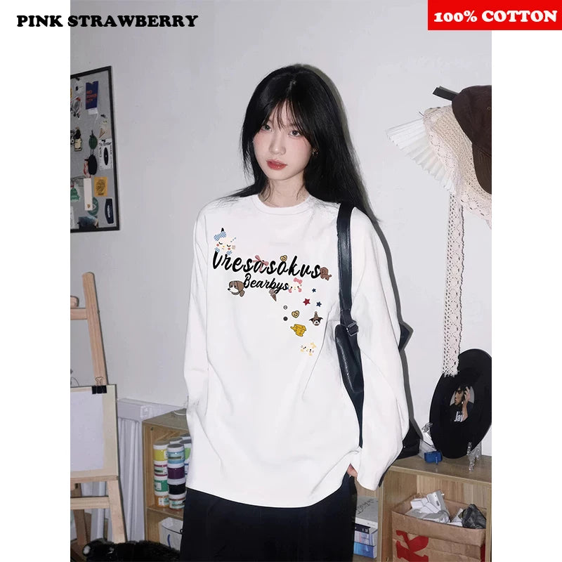 Person wearing a white sweatshirt with text and graphics, standing in a room with shelves and decor.