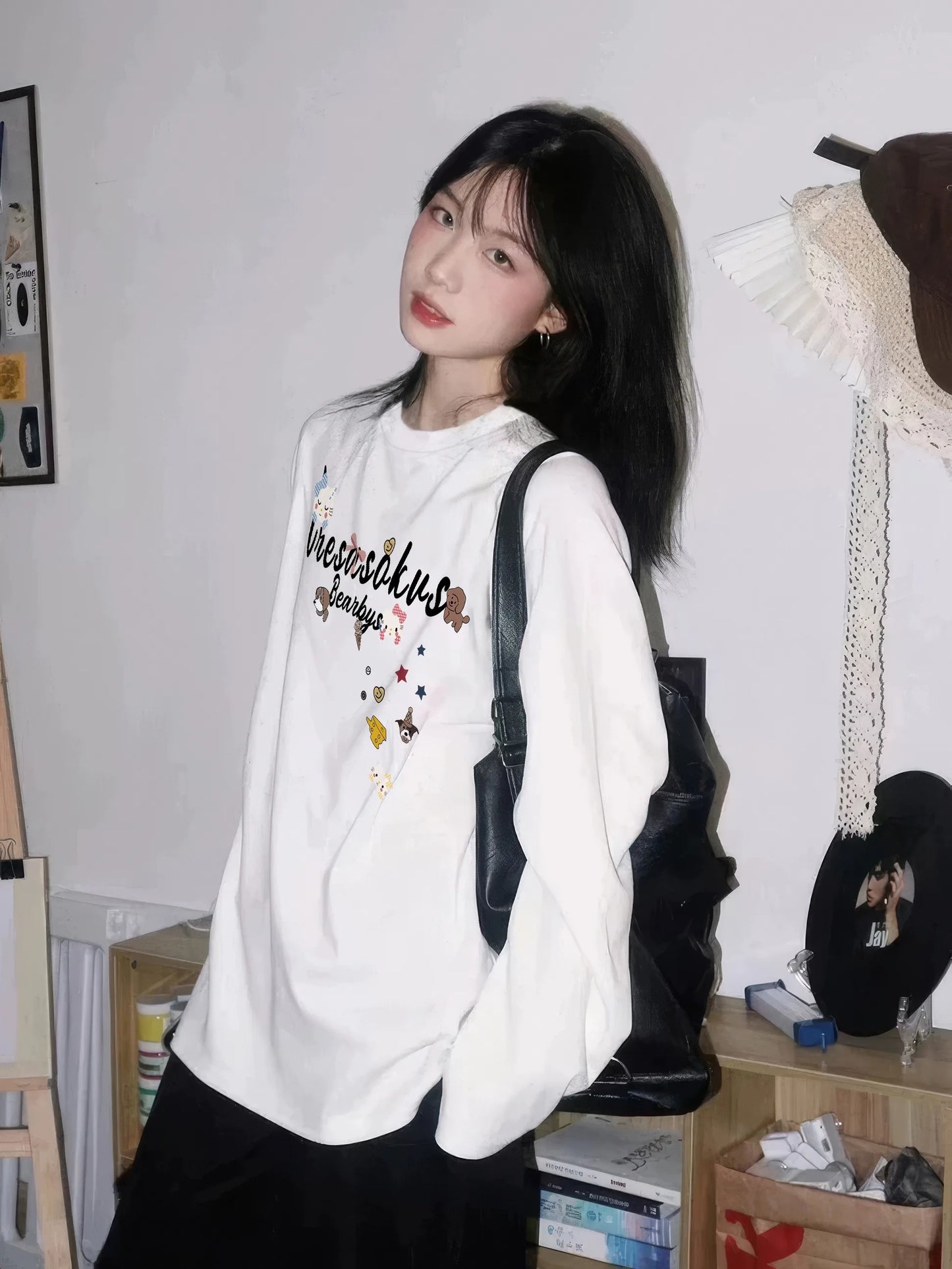 Person wearing a white hoodie with colorful text and graphics, standing indoors.