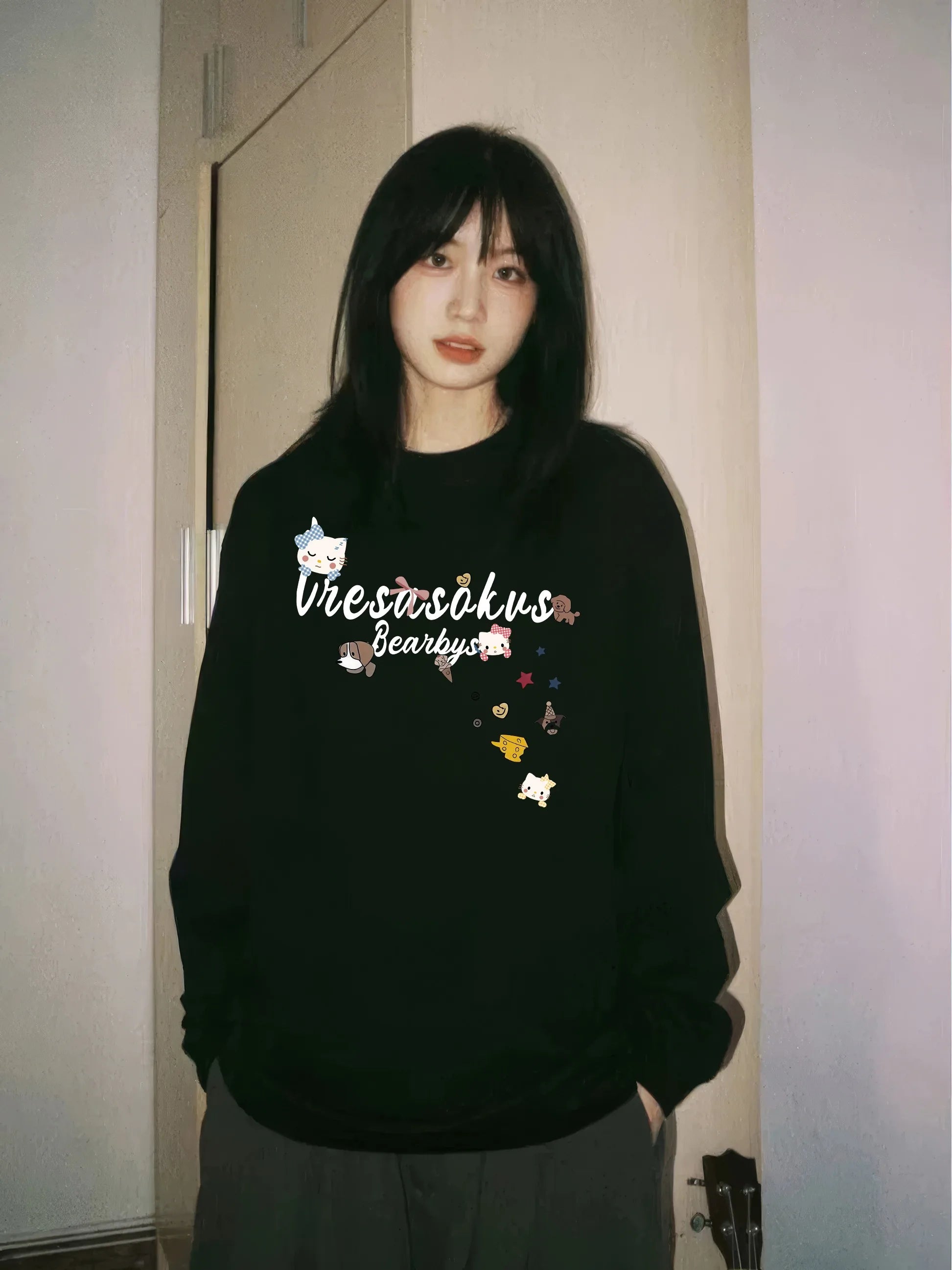 Person wearing a black sweatshirt with text and graphics in a room.