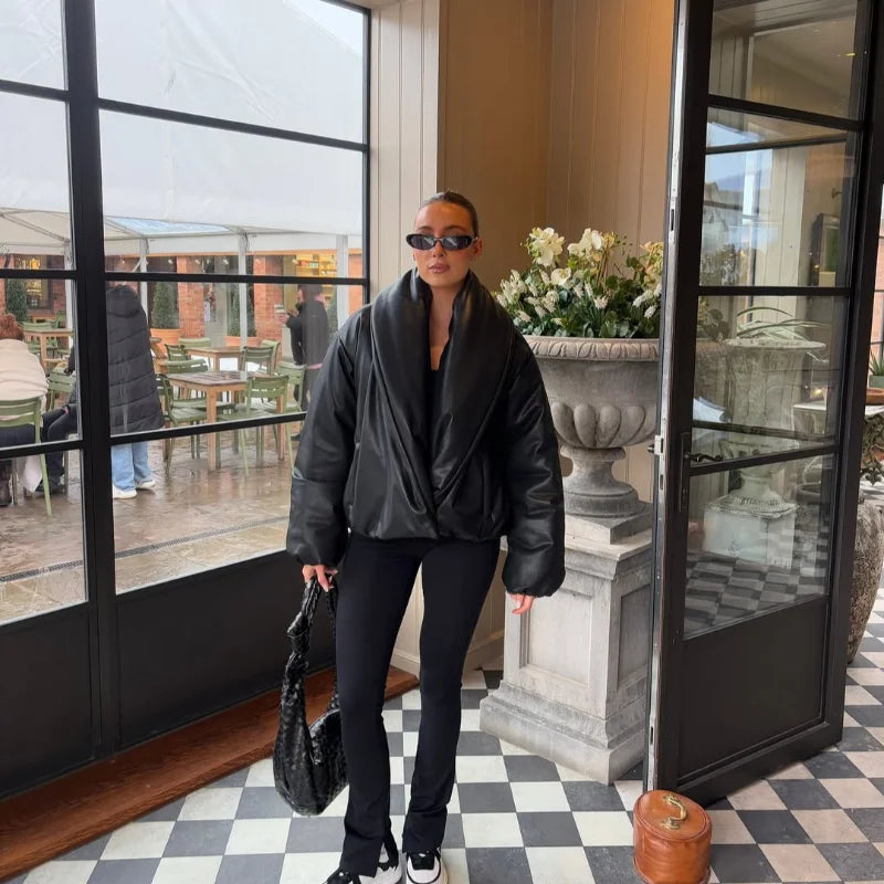 Person in black outfit standing in a modern interior setting with large windows and checkered floor.