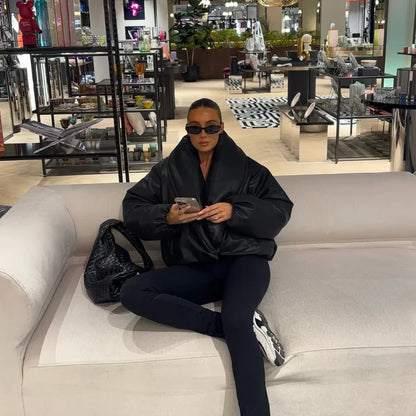 Person sitting on a couch in a modern indoor setting, possibly a mall or store.