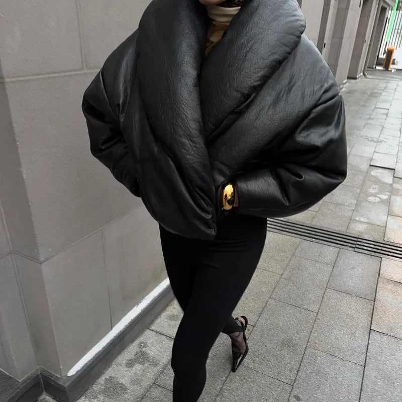 Person wearing a large black puffer jacket on a city street.