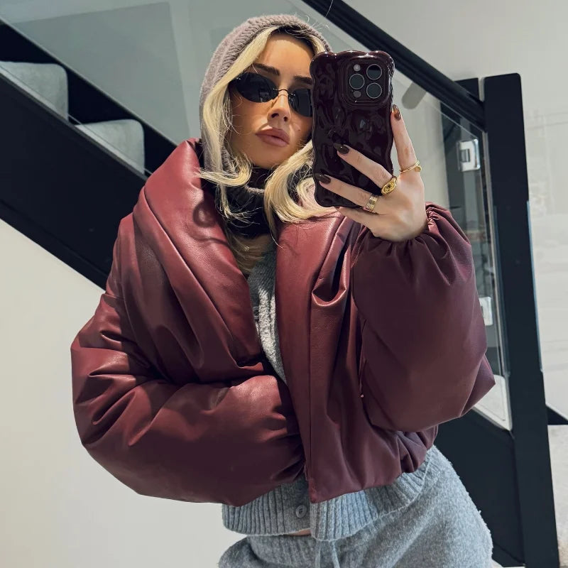 Person wearing a maroon jacket and sunglasses, taking a mirror selfie.