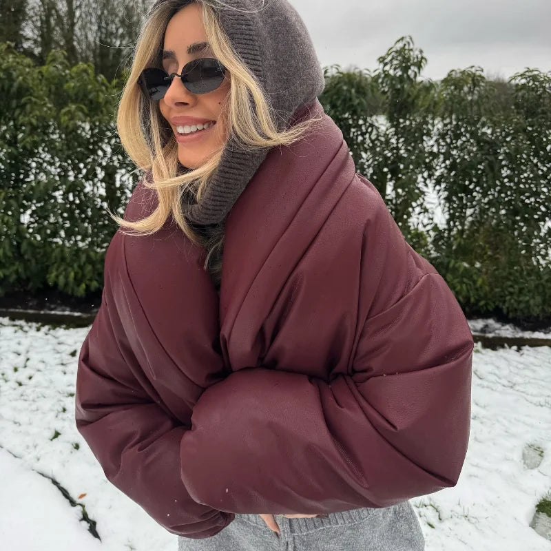 Woman wearing a maroon puffer coat and gray beanie in a snowy outdoor setting