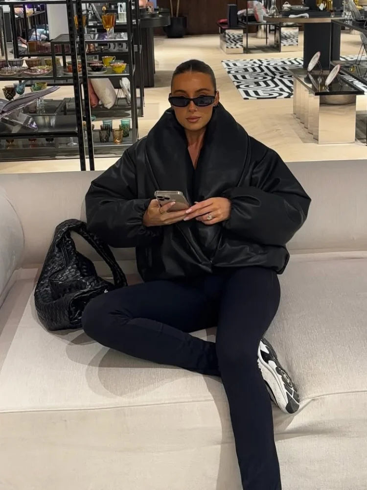 Person sitting on a couch in a modern interior setting, wearing a black outfit.