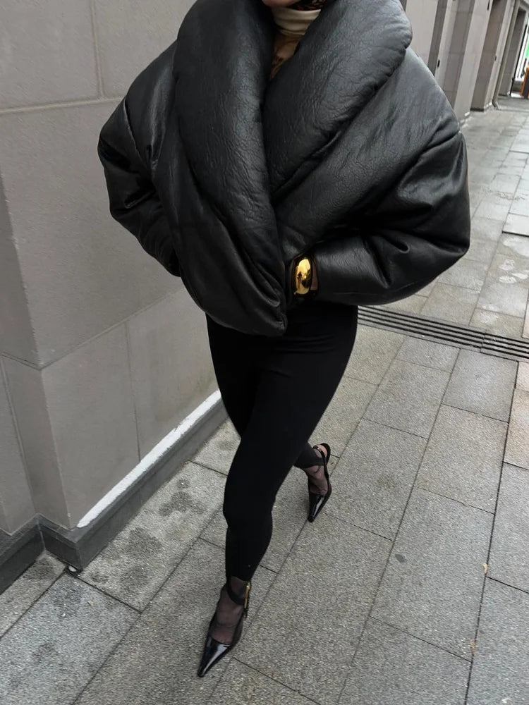 Person wearing a black puffer jacket and black pants on a sidewalk.