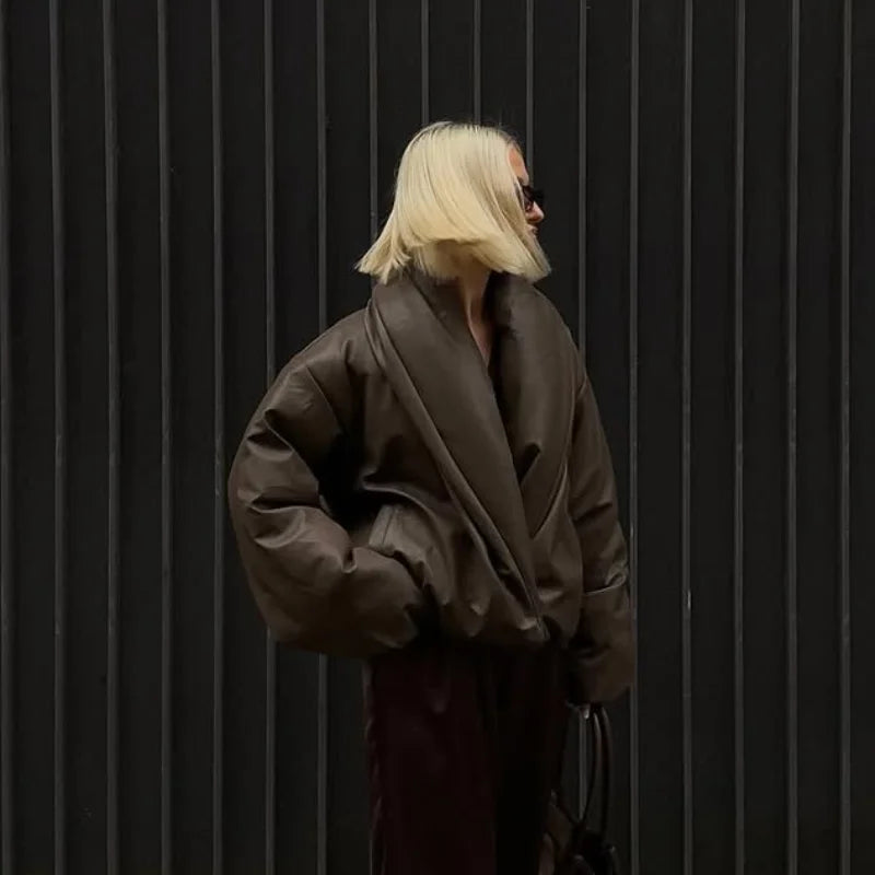 Person wearing a brown coat against a black background