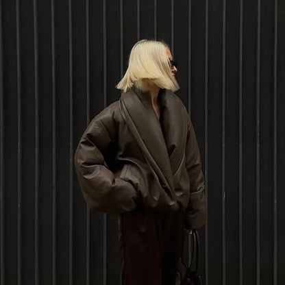 Person wearing a brown coat against a black background