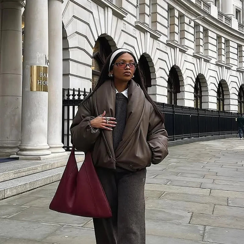 Person in formal attire with a red bag standing in front of a classical building.